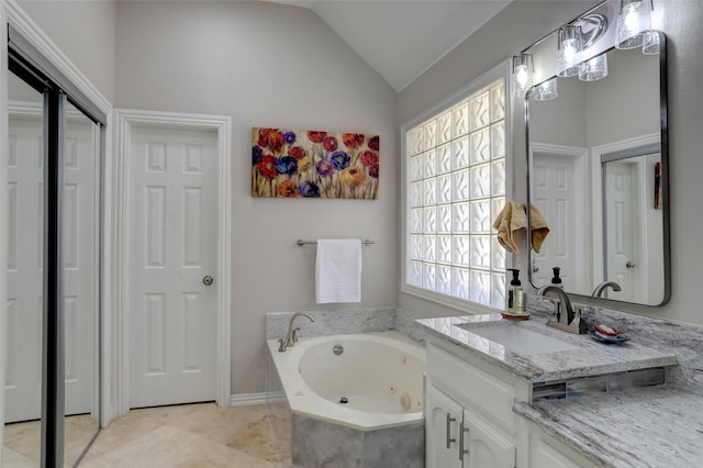 full bathroom featuring vanity, lofted ceiling, a jetted tub, and tile patterned floors