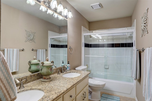 full bath featuring double vanity, toilet, bath / shower combo with glass door, and a sink