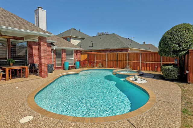 view of pool with a patio, fence, and a pool with connected hot tub