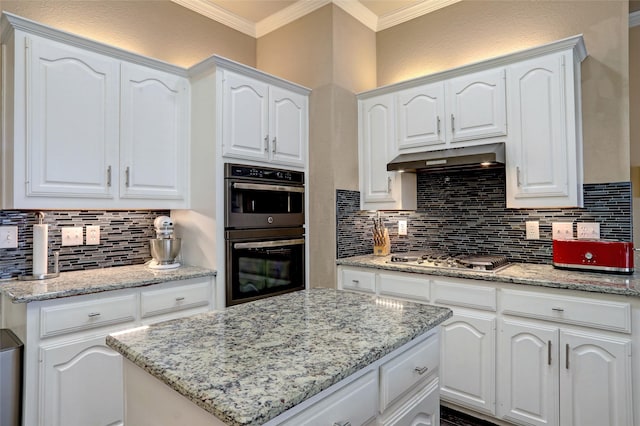 kitchen with double wall oven, under cabinet range hood, tasteful backsplash, crown molding, and stainless steel gas cooktop