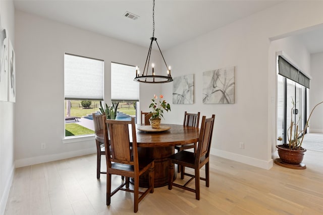 dining room with a chandelier, visible vents, light wood-style flooring, and baseboards