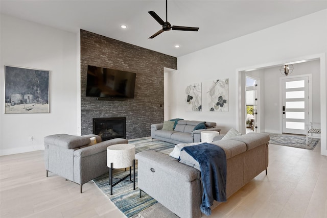 living room featuring light wood finished floors, recessed lighting, a fireplace, ceiling fan, and baseboards