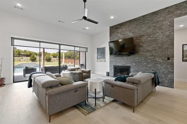 living room with a ceiling fan, visible vents, light wood-style flooring, and a fireplace