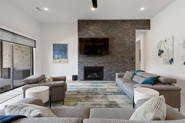living room with visible vents, a stone fireplace, and recessed lighting