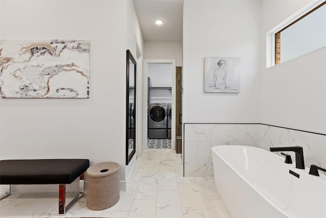 full bathroom featuring a freestanding tub, recessed lighting, marble finish floor, and washing machine and dryer