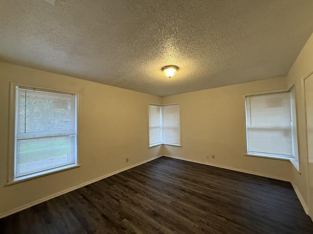 empty room with baseboards, dark wood-type flooring, and a textured ceiling