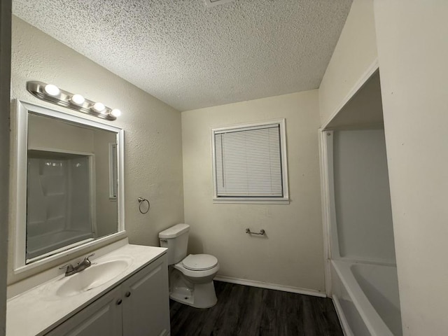 full bathroom featuring toilet, vanity, wood finished floors, a textured wall, and a textured ceiling