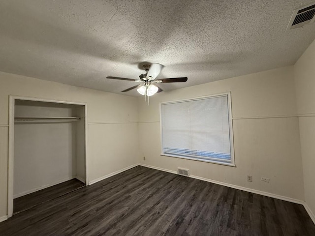 unfurnished bedroom with a closet, visible vents, dark wood-style flooring, and ceiling fan