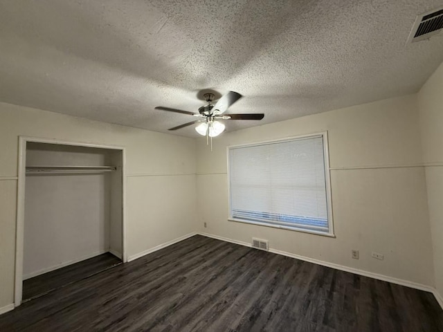 unfurnished bedroom featuring ceiling fan, visible vents, a closet, and dark wood finished floors