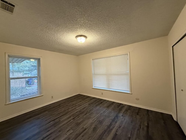 unfurnished bedroom with a closet, visible vents, baseboards, and dark wood-style flooring