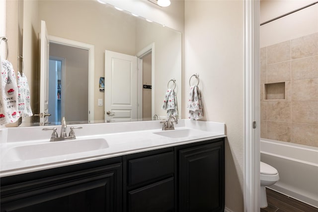 full bathroom with double vanity, toilet, washtub / shower combination, and a sink