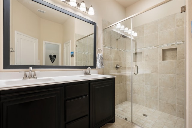 full bath with double vanity, a stall shower, visible vents, and a sink