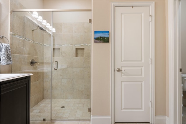 bathroom with vanity, toilet, baseboards, and a stall shower