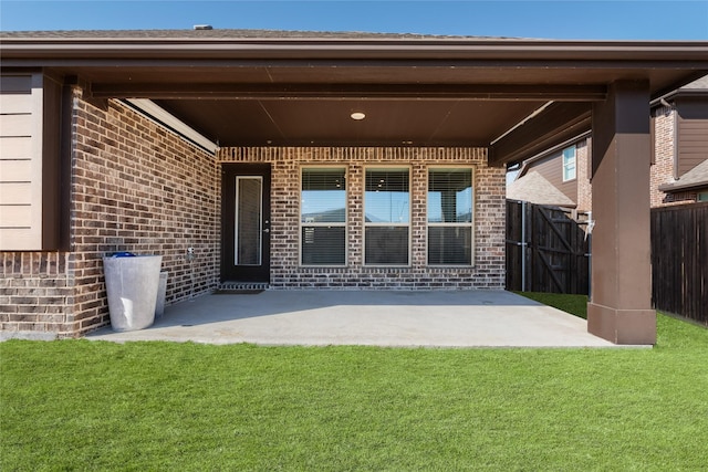 rear view of house with a yard, brick siding, a patio area, and fence