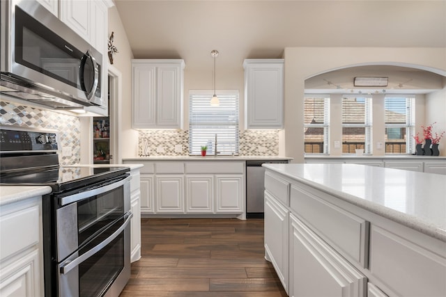 kitchen with dark wood-style flooring, white cabinets, stainless steel appliances, and a sink