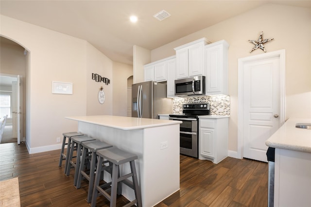 kitchen with a kitchen bar, visible vents, tasteful backsplash, arched walkways, and appliances with stainless steel finishes