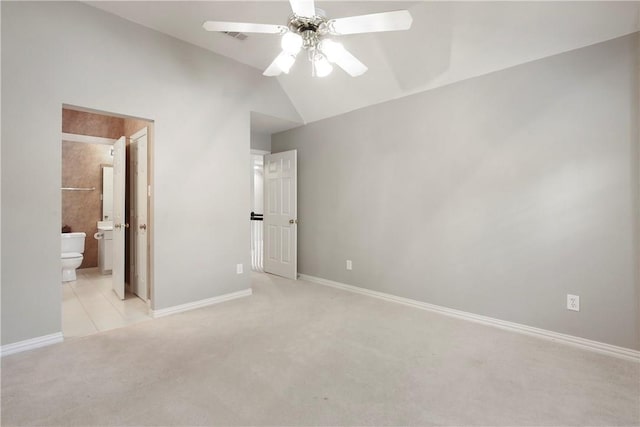 unfurnished bedroom with baseboards, lofted ceiling, light colored carpet, and ensuite bath