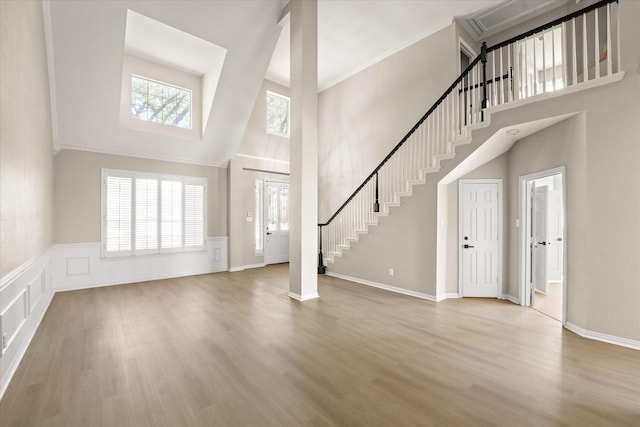 foyer entrance featuring stairway, wood finished floors, wainscoting, and ornamental molding