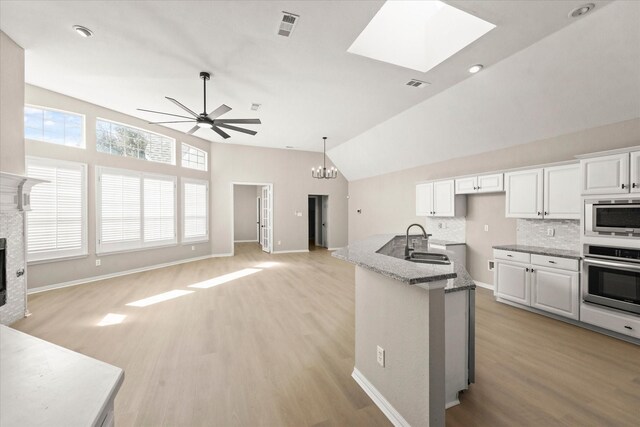 kitchen with visible vents, oven, open floor plan, a fireplace, and a sink