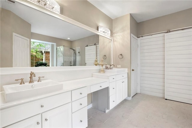 bathroom featuring double vanity, a stall shower, and a sink