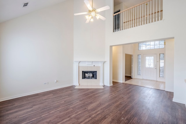 unfurnished living room featuring visible vents, baseboards, wood finished floors, and a tiled fireplace