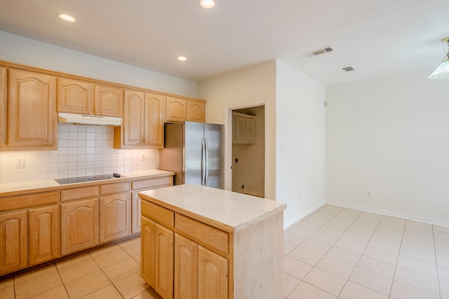 kitchen featuring visible vents, freestanding refrigerator, light countertops, under cabinet range hood, and black electric cooktop