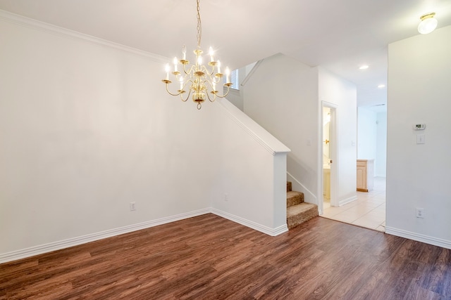 empty room with ornamental molding, wood finished floors, recessed lighting, baseboards, and stairs