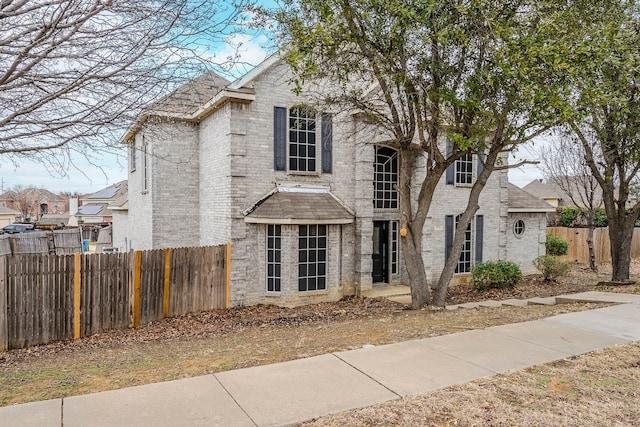 traditional-style home with fence and brick siding