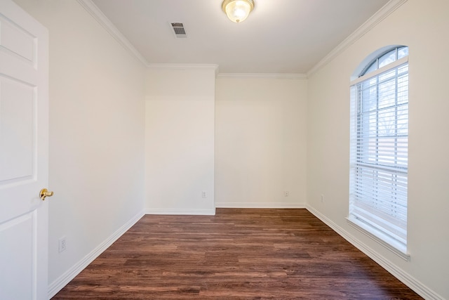 empty room featuring dark wood finished floors, baseboards, visible vents, and ornamental molding