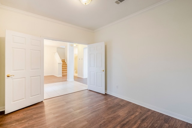 spare room featuring stairs, wood finished floors, baseboards, and ornamental molding