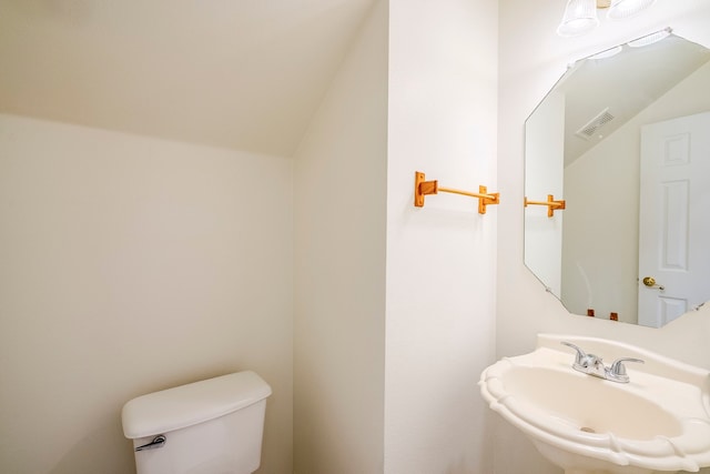 bathroom with vaulted ceiling, toilet, visible vents, and a sink