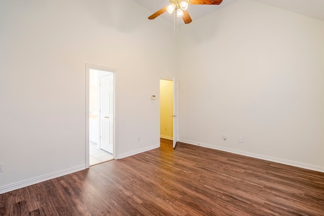 spare room with baseboards, high vaulted ceiling, wood finished floors, and a ceiling fan