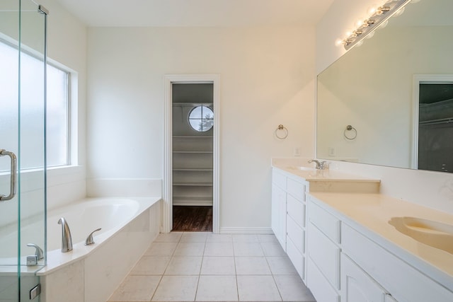 bathroom featuring a garden tub, a sink, tile patterned flooring, double vanity, and a spacious closet