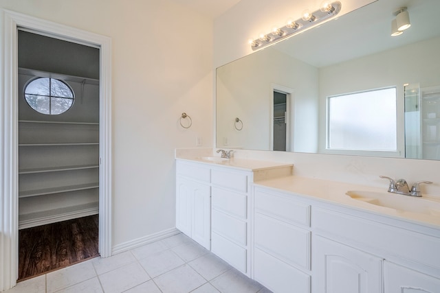 bathroom featuring tile patterned flooring, double vanity, walk in shower, and a sink