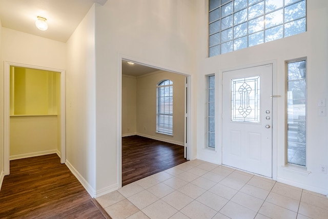 foyer entrance featuring light tile patterned flooring, baseboards, and a towering ceiling