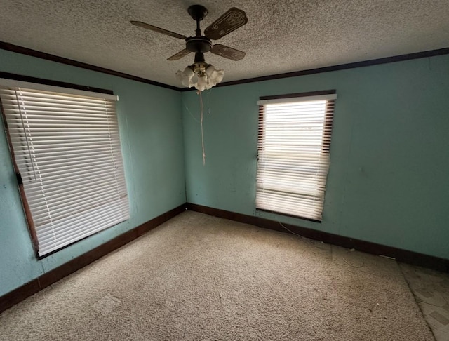 carpeted spare room featuring crown molding, a ceiling fan, baseboards, and a textured ceiling