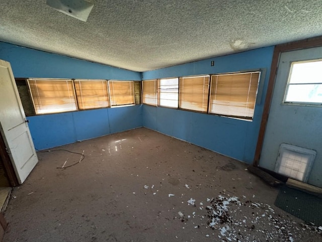 empty room with lofted ceiling and a textured ceiling