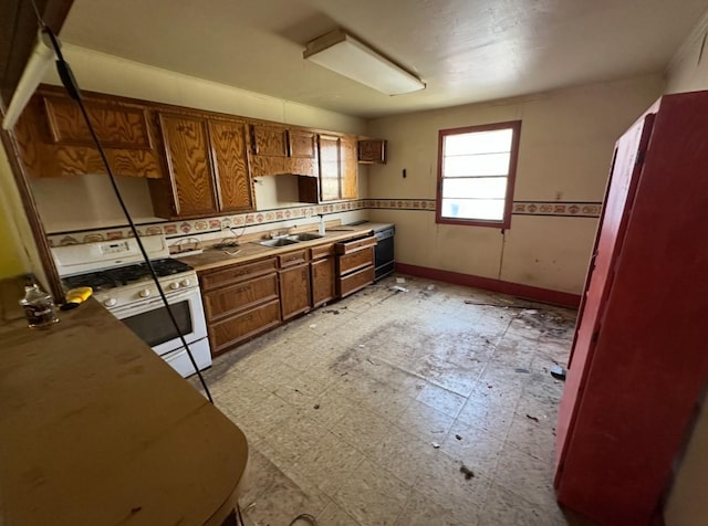 kitchen featuring gas range gas stove, light floors, decorative backsplash, brown cabinetry, and a sink