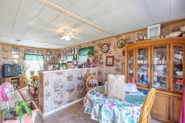 dining room featuring wooden walls, visible vents, and ceiling fan