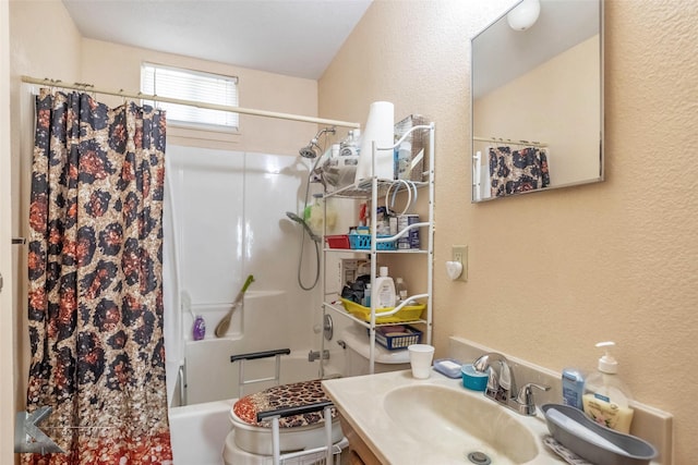 bathroom with shower / bath combo with shower curtain, vanity, and a textured wall