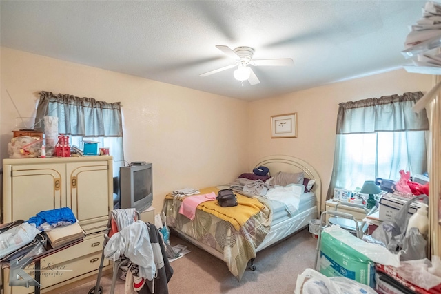 carpeted bedroom featuring a textured ceiling and a ceiling fan