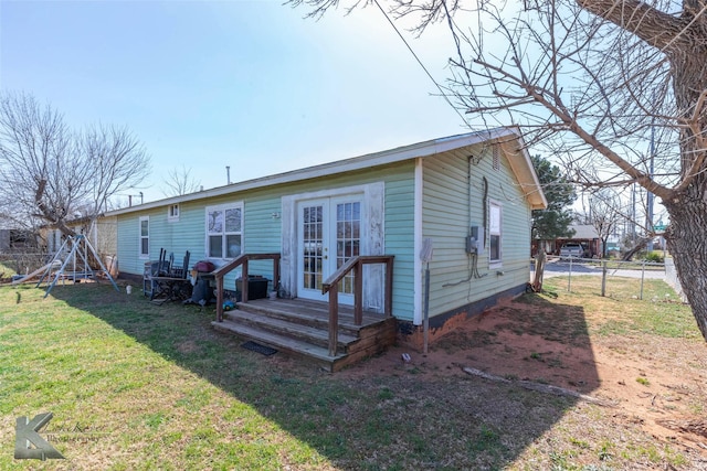 rear view of house featuring a lawn, french doors, and fence