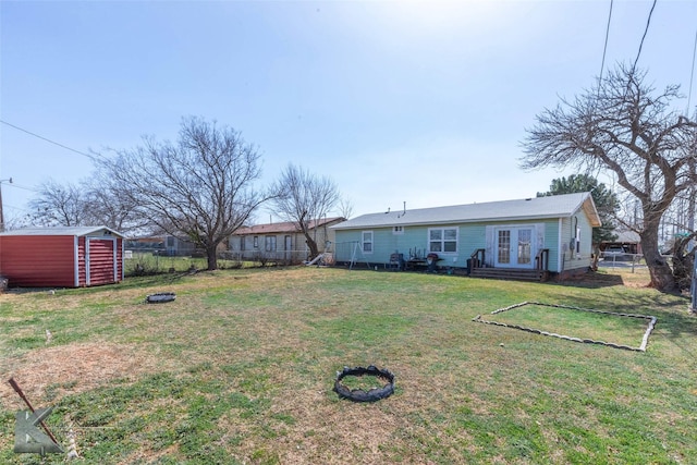 view of yard featuring french doors, a storage unit, an outdoor structure, and fence