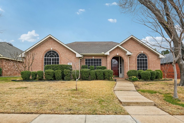 single story home featuring a front yard, brick siding, and roof with shingles