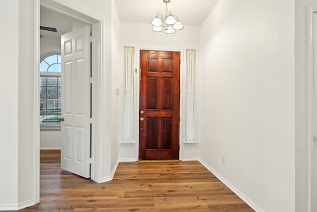 foyer entrance with baseboards, an inviting chandelier, and wood finished floors