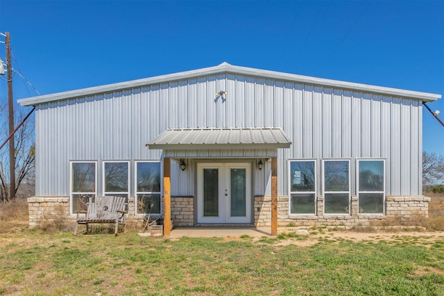 view of front of home with board and batten siding, a front lawn, french doors, and stone siding