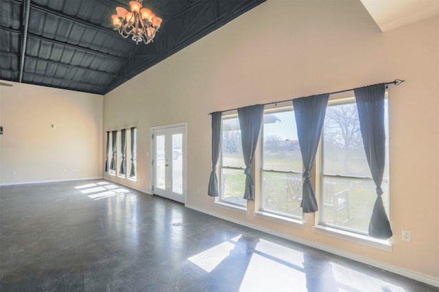 unfurnished room featuring baseboards, a chandelier, finished concrete floors, french doors, and high vaulted ceiling