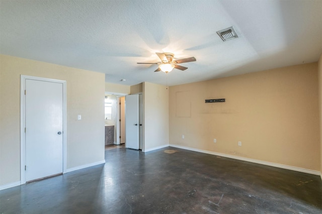 spare room with baseboards, visible vents, ceiling fan, finished concrete floors, and a textured ceiling