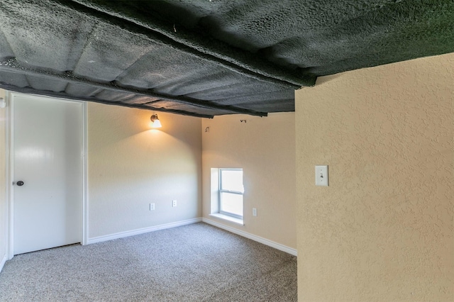 carpeted empty room featuring baseboards and a textured wall