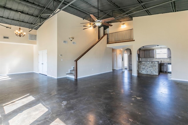 unfurnished living room with visible vents, ceiling fan with notable chandelier, arched walkways, concrete flooring, and stairs